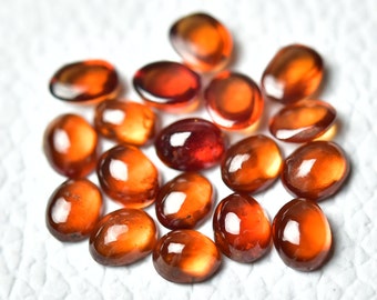 May include: A collection of 17 oval-shaped, polished gemstones. The stones are a deep orange-red color and have a glossy finish.