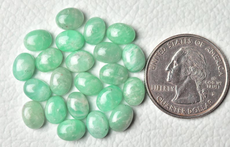 Peut inclure: Une collection de 20 pierres pr&eacute;cieuses vertes de forme ovale, chacune d'environ la taille d'une pi&egrave;ce de 25 cents am&eacute;ricaine. Les pierres ont une apparence translucide l&eacute;g&egrave;rement nuageuse.