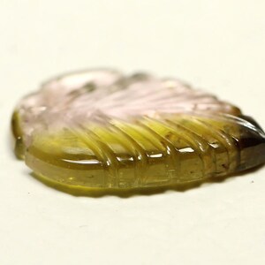 May include: A carved green, pink, and brown gemstone in the shape of a leaf.