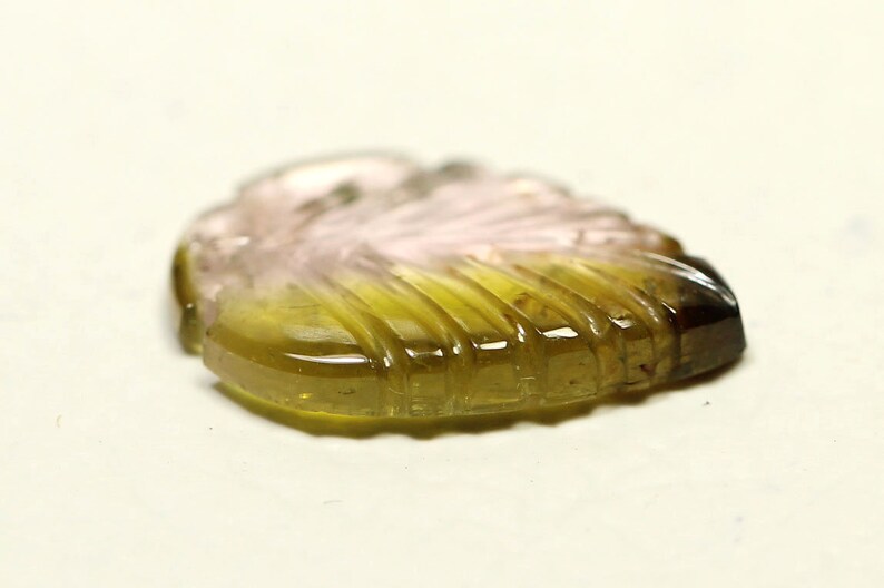 May include: A carved green, pink, and brown gemstone in the shape of a leaf.