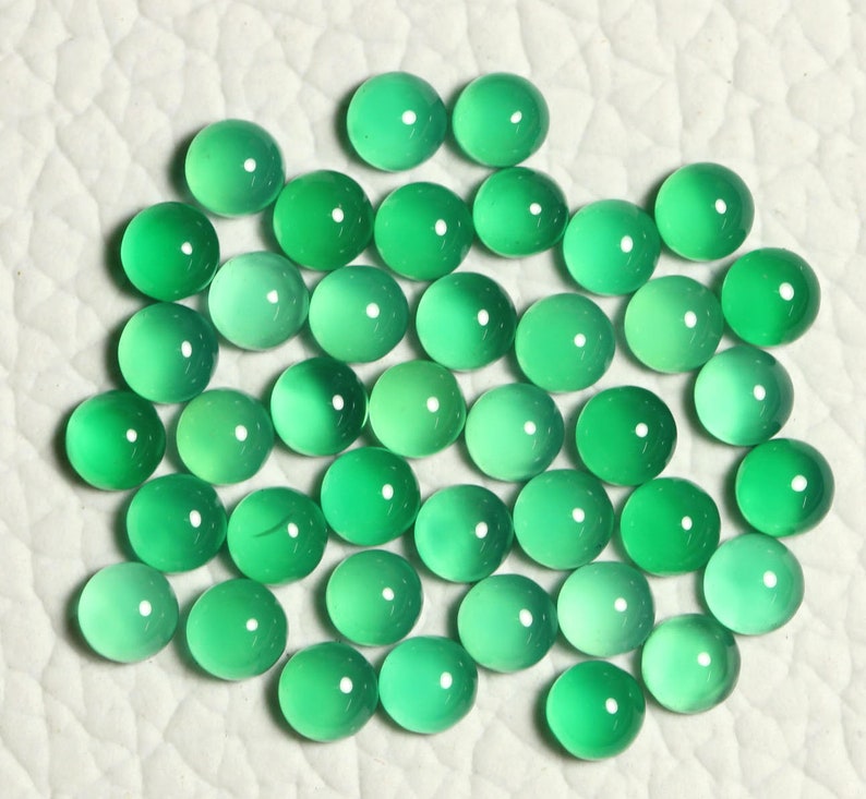 Puede incluir: Una colecci&oacute;n de 40 piedras preciosas redondas y verdes en cabuj&oacute;n. Las piedras son lisas y pulidas, con una apariencia transl&uacute;cida.