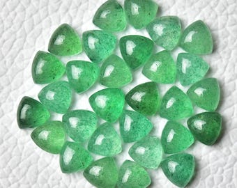 Puede incluir: Una colección de 25 piedras preciosas cabujón triangulares verdes. Las piedras son translúcidas y tienen un aspecto moteado.