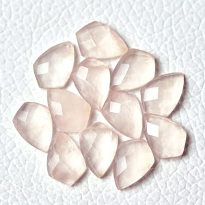 May include: A collection of 12 faceted rose quartz gemstone beads in a pale pink color. The beads are shaped like teardrops and have a smooth, polished finish.
