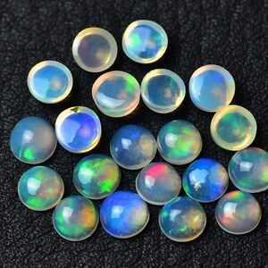 May include: A collection of 17 round, iridescent opal cabochons in various shades of white, blue, green, and pink. The cabochons are approximately 6mm in diameter and have a smooth, polished surface.