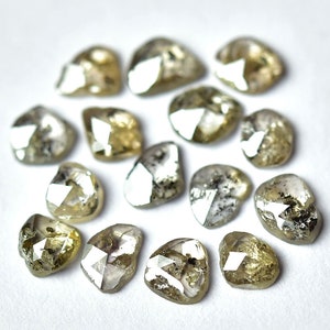 May include: A collection of rough, unpolished diamonds in various shades of gray and brown. The diamonds are heart-shaped and have a natural, raw appearance.