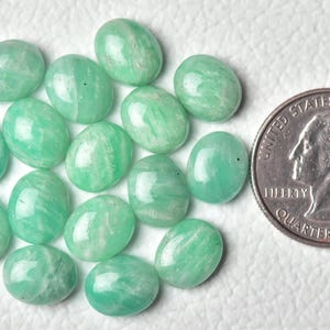May include: A collection of 15 oval-shaped green aventurine gemstones, each approximately the size of a US quarter.