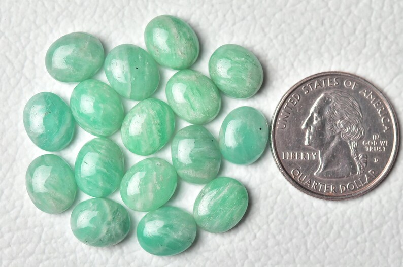 May include: A collection of 15 oval-shaped green aventurine gemstones, each approximately the size of a US quarter.