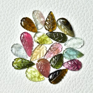 May include: Assortment of carved gemstone leaf shapes in various colors, including pink, green, brown, and clear. The leaves are approximately 1 inch in length.