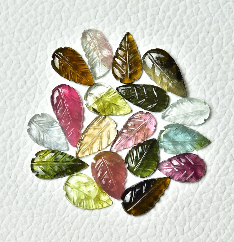 May include: Assortment of carved gemstone leaf shapes in various colors, including pink, green, brown, and clear. The leaves are approximately 1 inch in length.