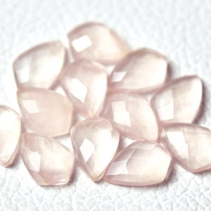 May include: A collection of pale pink, faceted, teardrop-shaped gemstone beads.