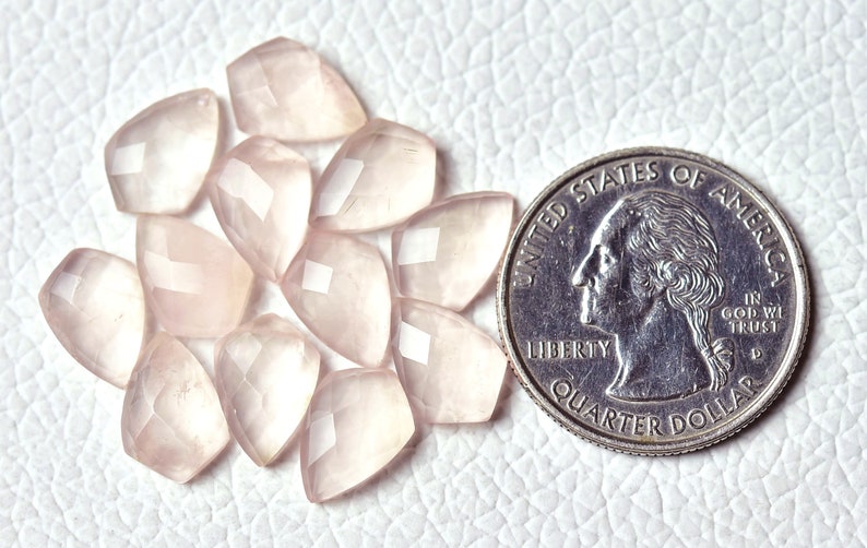 May include: Ten faceted rose quartz stones, each about the size of a US quarter, arranged in a circle on a white surface.