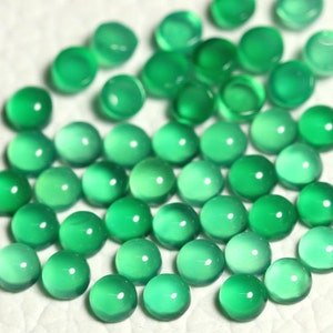 Puede incluir: Una colecci&oacute;n de cabujones redondos de piedras preciosas verdes. Los cabujones son lisos y pulidos, con una apariencia transl&uacute;cida.