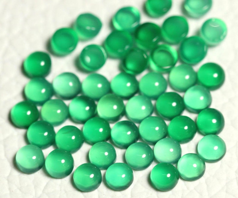 Puede incluir: Una colecci&oacute;n de cabujones redondos de piedras preciosas verdes. Los cabujones son lisos y pulidos, con una apariencia transl&uacute;cida.