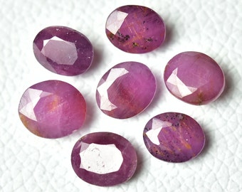 May include: Seven oval-shaped pink gemstones with a faceted cut. The gemstones have a pink hue with a slight orange tint.