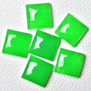 Könnte beinhalten: Sechs quadratische, grüne Edelsteine mit glänzender Oberfläche. Die Edelsteine sind in einer Gruppe auf einer weißen Oberfläche angeordnet.