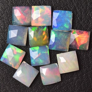 Può includere: Assortimento di 12 pietre preziose di opale di forma quadrata in vari colori, tra cui bianco, blu, verde e arancione. Gli opali sono tagliati e lucidati, con una superficie sfaccettata.