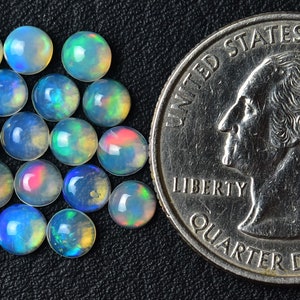 May include: A group of 20 iridescent opal cabochons, each approximately the size of a US quarter.