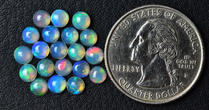 May include: A group of 20 iridescent opal cabochons, each approximately the size of a US quarter.