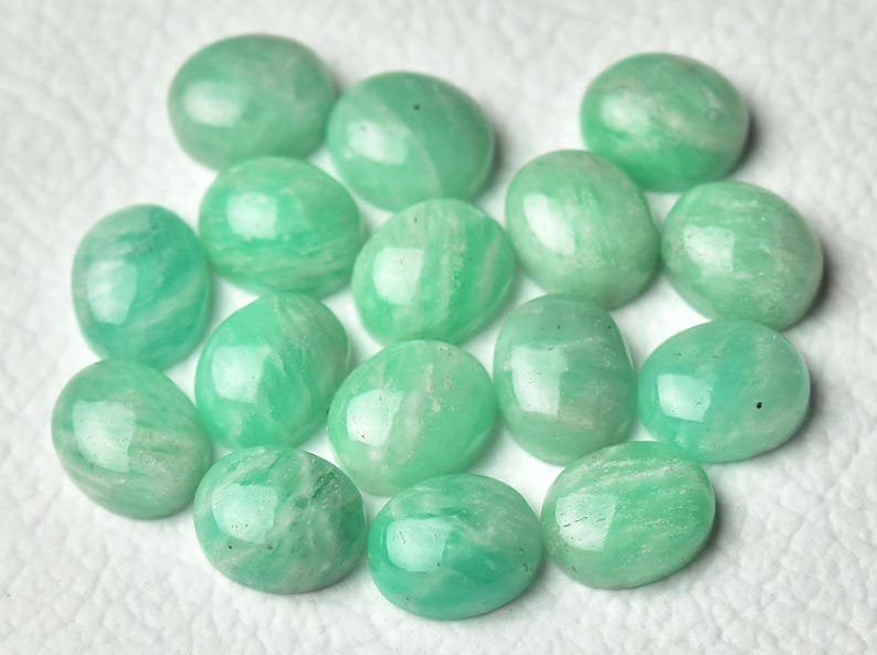 May include: A collection of 14 smooth, oval-shaped green gemstones. The stones have a translucent, light green color and a slightly cloudy appearance.