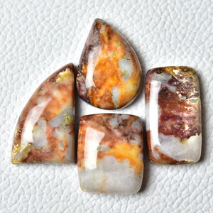 May include: Five polished gemstone cabochons in various shapes and sizes. The stones are a mix of white, brown, and orange with a marbled pattern.