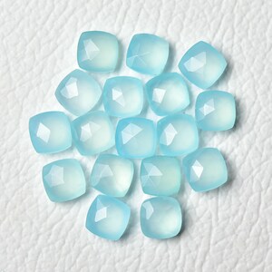 K&ouml;nnte beinhalten: Eine Sammlung von 18 hellblauen, facettierten, quadratischen Chalcedon-Edelsteinen.