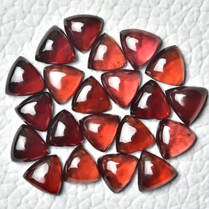 May include: A collection of 20 red triangular gemstone cabochons. The gemstones are faceted and have a glossy finish.