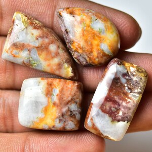 May include: Four polished, white, brown, and orange agate cabochons with a variety of patterns and textures.