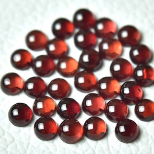 Könnte beinhalten: Eine Sammlung von 25 runden, roten Edelstein-Cabochons. Die Cabochons sind glatt und poliert, mit einem glänzenden Finish.