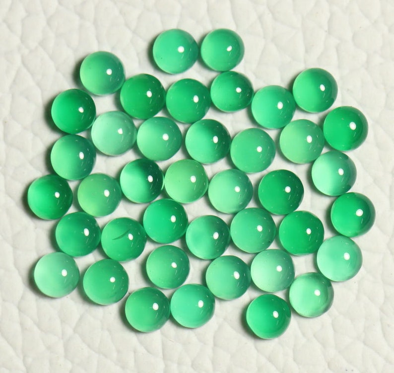 Puede incluir: Una colecci&oacute;n de 40 cabujones redondos de piedra preciosa verde. Los cabujones son lisos y pulidos, con una ligera variaci&oacute;n en el color y la translucidez.