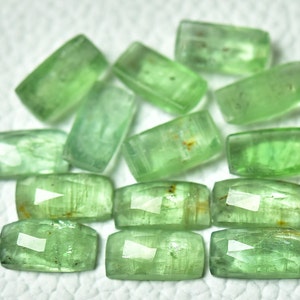 May include: A collection of twelve green gemstone rectangular cabochons. The stones have a translucent, slightly cloudy appearance with a light green hue.
