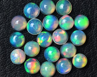 May include: A collection of round, iridescent opal cabochons in various shades of blue, green, and pink. The opals are smooth and polished, with a high luster.
