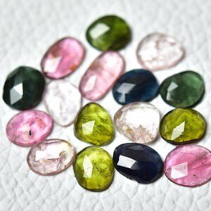 May include: Assortment of faceted gemstones in various colors, including pink, green, blue, and clear. The gemstones are oval and heart-shaped.