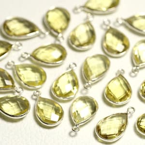 Op de afbeelding: Een verzameling van 20 druppelvormige, gefacetteerde, gele citrien edelsteen hangers met zilverkleurige springringen.