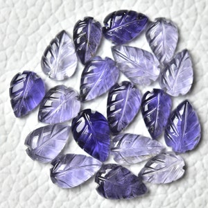 May include: A collection of 18 purple amethyst gemstone leaf shaped beads. The beads are carved with a leaf design and have a translucent appearance.