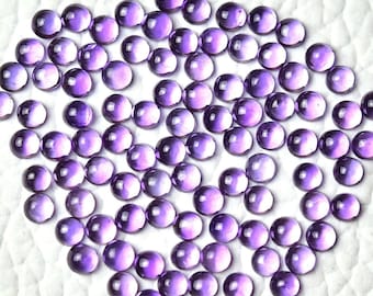 May include: A collection of round, purple amethyst cabochons. The cabochons are smooth and polished, with a slight shimmer.