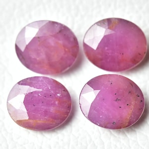 Può includere: Quattro pietre preziose ovali di colore rosa con taglio a faccette. Le pietre preziose hanno un aspetto traslucido con un leggero luccichio.