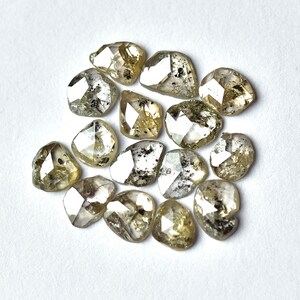 May include: A collection of 14 rough, faceted, and translucent diamonds with a light green and gray color.
