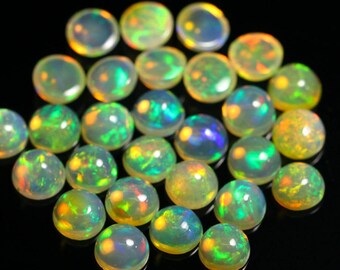 May include: A collection of 25 round, iridescent opal cabochons. The opals are a mix of green, yellow, and orange colors. The cabochons are all approximately the same size and shape.