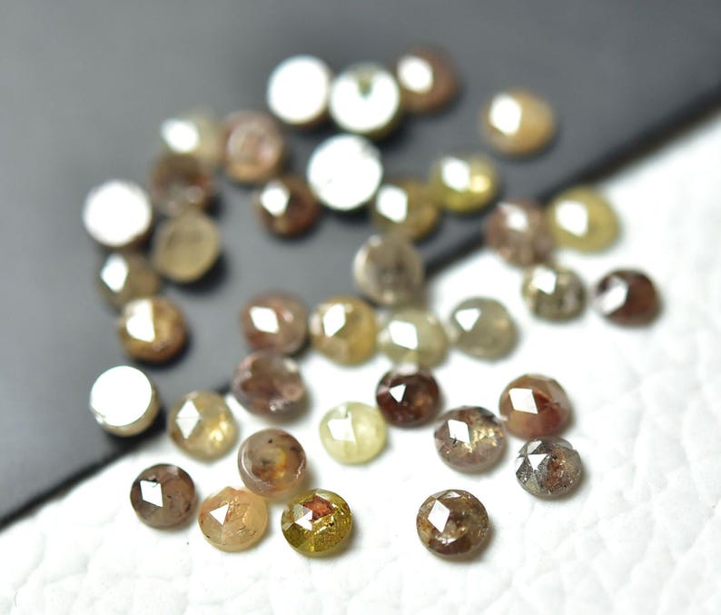 Op de afbeelding: Een verzameling bruine, grijze en gele ruwe diamanten, ook wel ruwe diamanten genoemd, met een gefacetteerde, ronde vorm. Deze diamanten zijn perfect voor het maken van sieraden en handwerk.