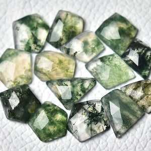 Może przedstawiać: Kolekcja 12 zielonych kaboszonów z agatu mchowego, każdy z unikalnym wzorem zieleni i bieli. Kamienie są oszlifowane w kształcie fasetowym i mają gładkie, polerowane wykończenie.