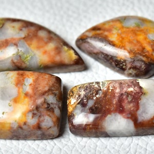 May include: Four polished, multi-colored agate cabochons with a white, brown, and orange color scheme. The cabochons are cut in different shapes, including rectangular and teardrop.
