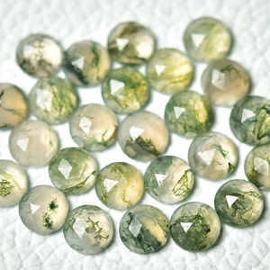 May include: A collection of 20 faceted moss agate gemstones. The stones are a mix of green and white with a translucent appearance.