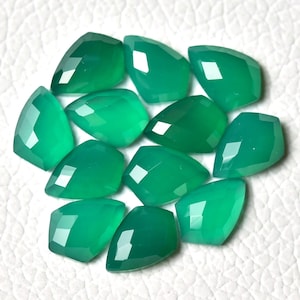May include: A group of 10 green gemstone cabochons, each with a faceted, teardrop shape. The stones are arranged in a loose cluster on a white surface.