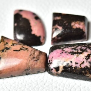 May include: Four pink and black gemstone cabochons in different shapes, including a triangle, a square, and two half-circles.