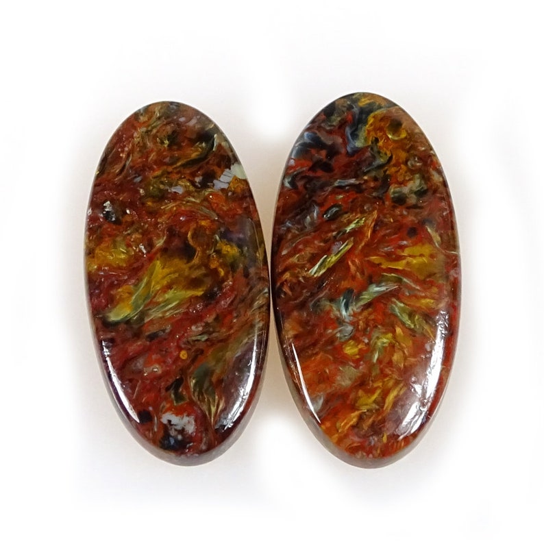 May include: Two oval-shaped tiger's eye cabochons with a red, gold, and blue swirling pattern.