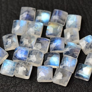 May include: A collection of 20 iridescent white moonstone square cabochons. The stones have a blue sheen and are perfect for jewelry making.
