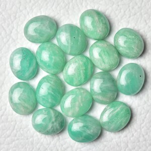 May include: A collection of 15 oval-shaped green gemstones, likely amazonite, with white streaks and a polished finish.