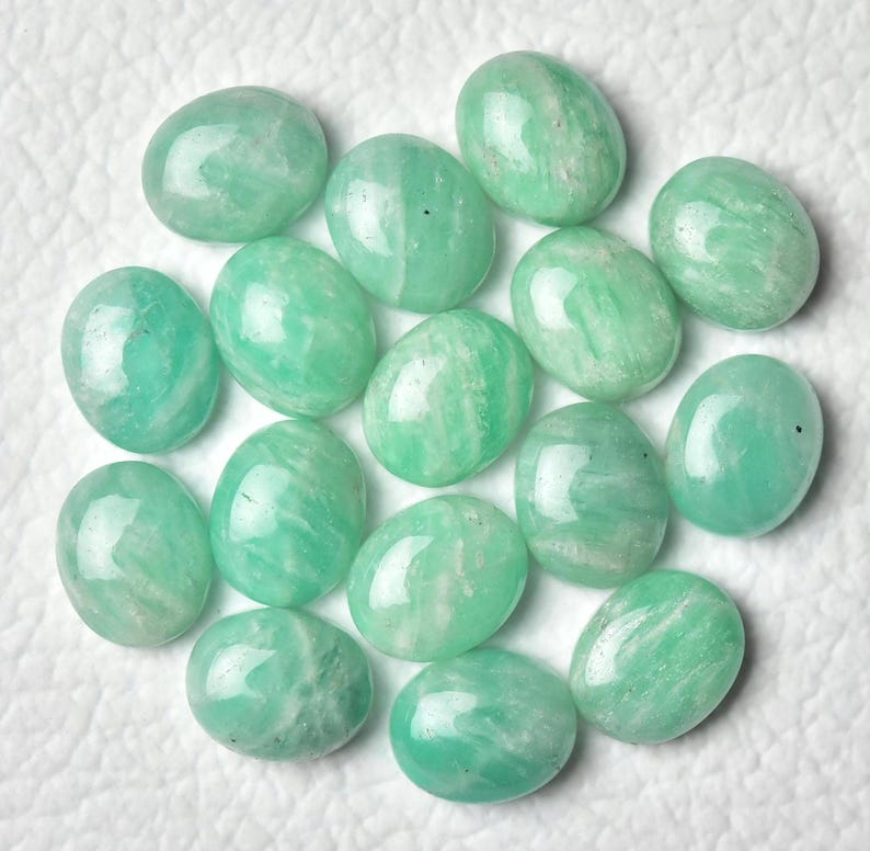 May include: A collection of 15 oval-shaped green gemstones, likely amazonite, with white streaks and a polished finish.