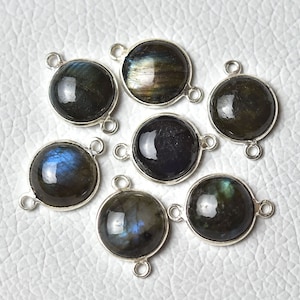 May include: Seven round, silver-toned, gemstone pendants with a dark blue and green iridescent finish. Each pendant has two loops for attaching to jewelry.