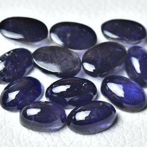 May include: A collection of ten oval-shaped, polished gemstones. The stones are a deep purple-blue colour and have a glossy finish.